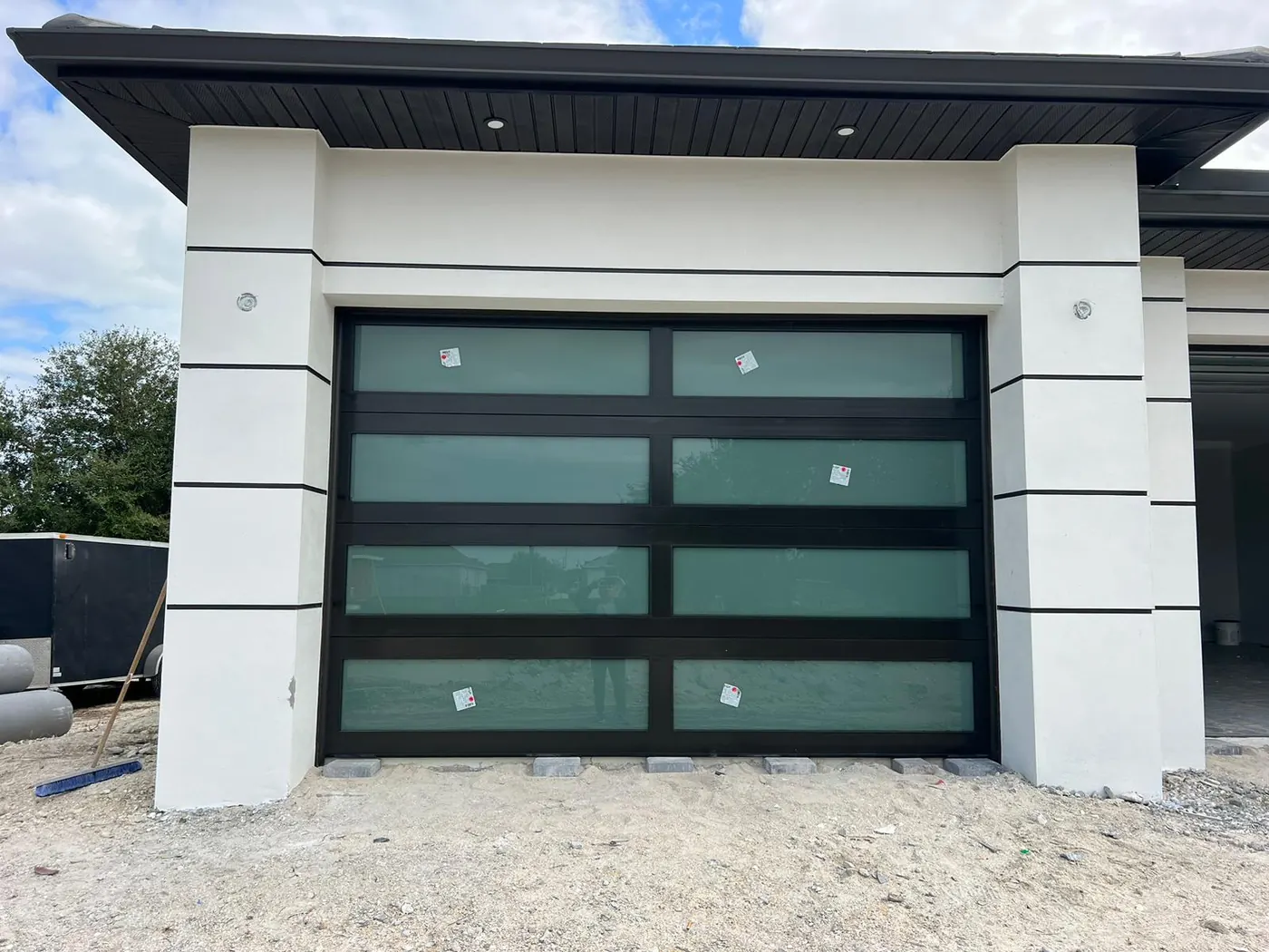 Black frame full-view hurricane impact glass garage door on a new-construction modern home